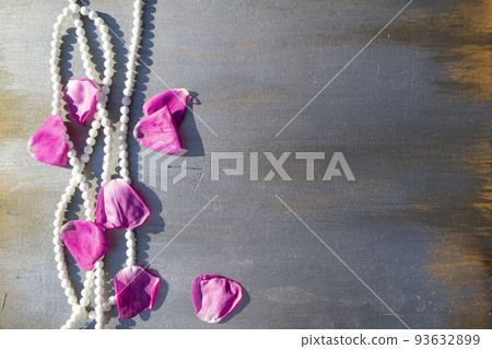Pearl beads and rose petals on a gray wooden background close-up. 93632899