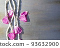 Pearl beads and rose petals on a gray wooden background close-up. 93632900