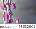 Pearl beads and rose petals on a gray wooden background close-up. 93632901