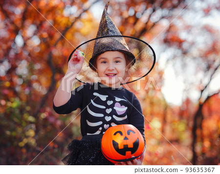 Young girl in black costume goes trick or treating Young girl in black costume goes trick or treating 93635367