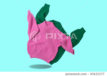 Two colored knitted sweaters, pink and green, sleeves up, as if dancing, concept, on a turquoise background Two colored knitted sweaters, pink and green, sleeves up, as if dancing, concept, on a turquoise background 93635377