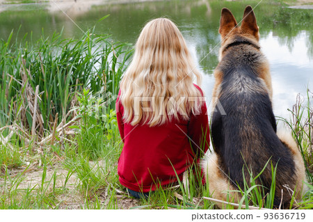 A woman with a dog sits on the shore of the - Stock Photo