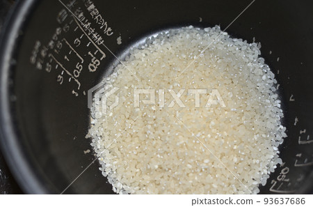 Putting white rice in the pot of an electric rice cooker 93637686