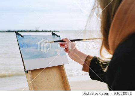 Faceless shot of a female drawing on a beach. en plein air artist 93638098
