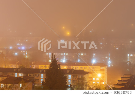 In apartment buildings lights are on in the night fog. Lights of night houses in dense fog. The windows of apartment buildings glow in the night fog. Blurred image In apartment buildings lights are on in the night fog. Lights of night houses in dense fog. The windows of apartment buildings glow in the night fog. Blurred image 93638793