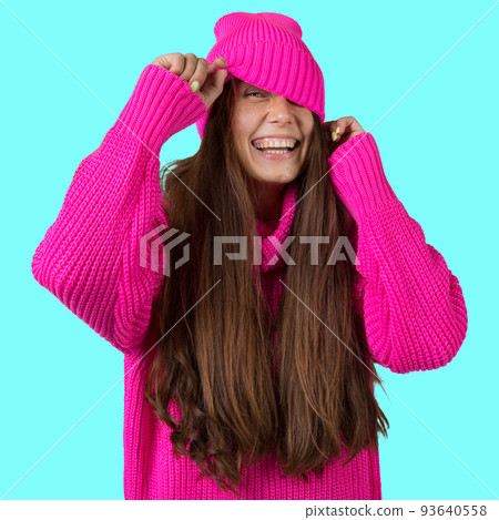 A young girl with long hair, in a crimson knitted sweater and a crimson hat, laughs merrily, peeking out from under the cap, concept A young girl with long hair, in a crimson knitted sweater and a crimson hat, laughs merrily, peeking out from under the cap, concept 93640558
