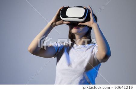 Metaverse technology concept. Woman with VR virtual reality goggles is playing a game with a friends in metaverse. Metaverse technology concept. Woman with VR virtual reality goggles is playing a game with a friends in metaverse. 93641219