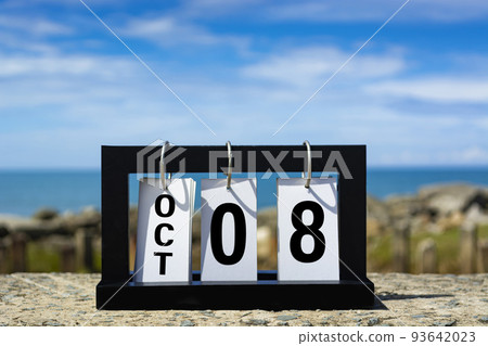 Oct 08 calendar date text on wooden frame with blurred background of ocean. 93642023