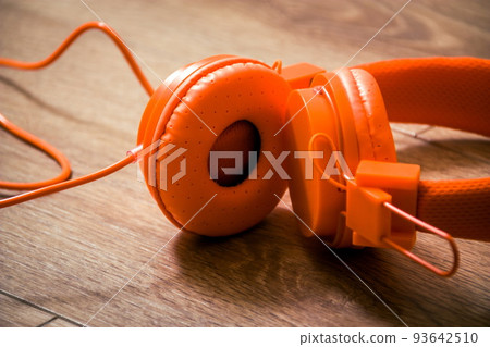 Modern orange headset headphones on the table Modern orange headset headphones on the table 93642510