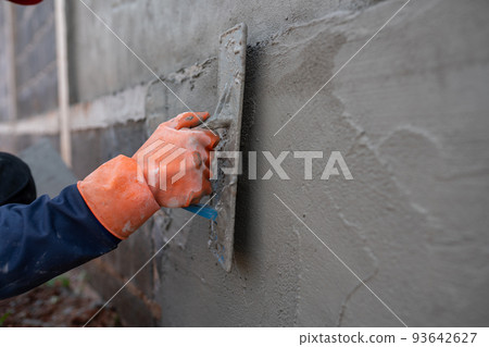 Masonry workers use cement trowels on construction sites. 93642627