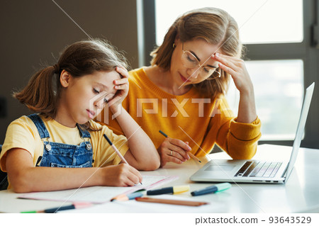 Confused mother doing homework with stressed daughter at home 93643529