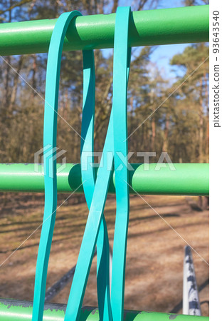 Close up picture of resistance band on bar at an outdoor gym, selective focus. 93643540