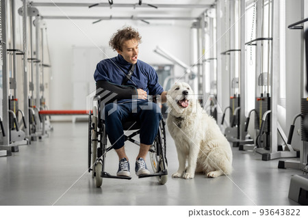 Guy with disabilities in a wheelchair with his assistance dog at rehabilitation center 93643822