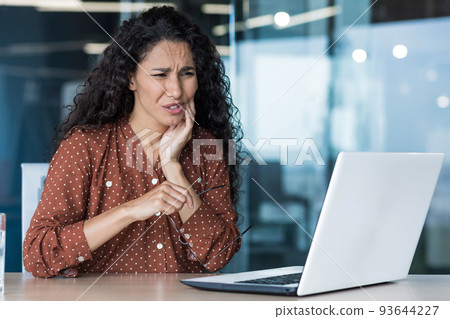 Beautiful business woman working inside office building, patient has severe toothache, worker uses laptop Beautiful business woman working inside office building, patient has severe toothache, worker uses laptop 93644227