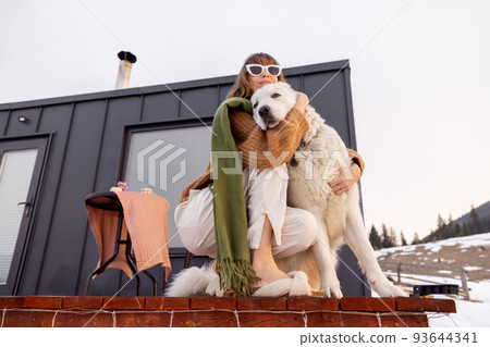 Woman with her dog resting on terrace of tiny house on nature 93644341