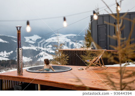 Woman swims in hot bath while resting at small modern house in the mountains Woman swims in hot bath while resting at small modern house in the mountains 93644394