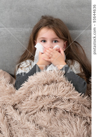 A cute little girl is lying in bed sick. A cute little girl is lying in bed sick. 93644636