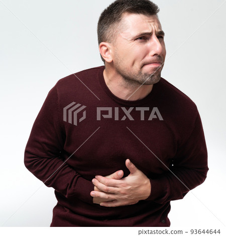A man touches his stomach with two hands, on a white background with copy space, Stomach pain in a man. A man touches his stomach with two hands, on a white background with copy space, Stomach pain in a man. 93644644