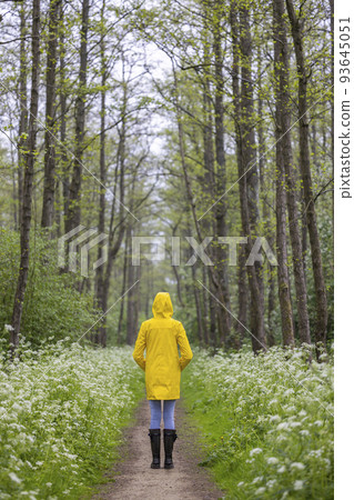 Young woman with yellow raincoat and rubber boots in spring nature 93645051