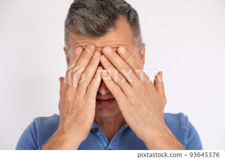 Close-up of mature man holding face in hands Close-up of mature man holding face in hands 93645376