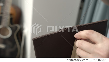 Sewing a brown leather wallet. Leather work. Sewing products by hand. Manufacture of leather goods. 93646385