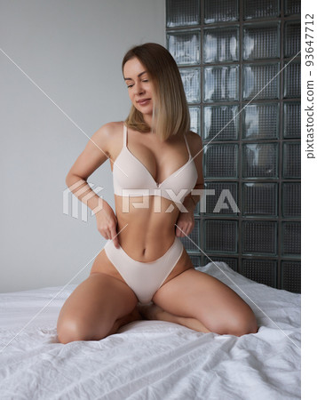 Young woman on her bed wearing white underwear. 93647712