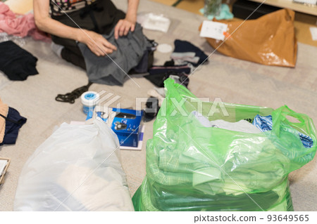 一位高級女性,她將不必要的衣服放入垃圾袋並扔掉。 一位高級女性,她將不必要的衣服放入垃圾袋並扔掉。 93649565