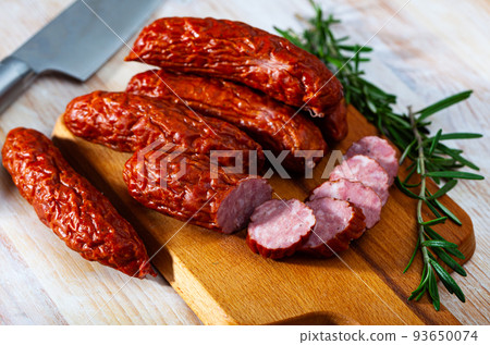 Sliced half-smoked sausages susena on wooden table. Sliced half-smoked sausages susena on wooden table. 93650074