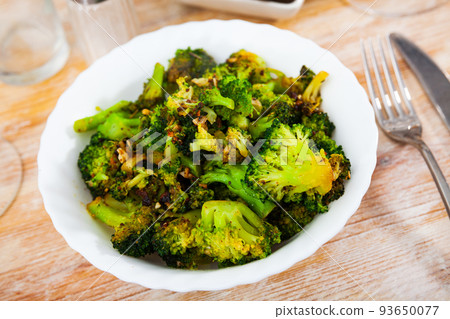 Fried broccoli with garlic served in white plate 93650077
