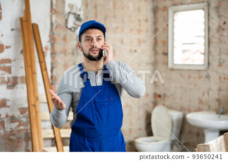 Builder talking on phone at construction site 93650241