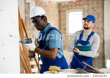 Man construction worker using demolition hammer in apartment 93650287