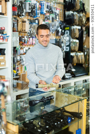Seller man at counter in weapon shop 93650411