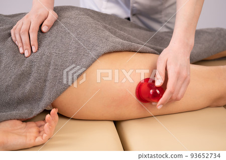 Woman on a session of anti-cellulite massage with a vacuum jar.  93652734