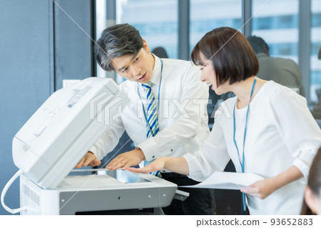 A female staff member teaching a veteran how to use a copier 93652883