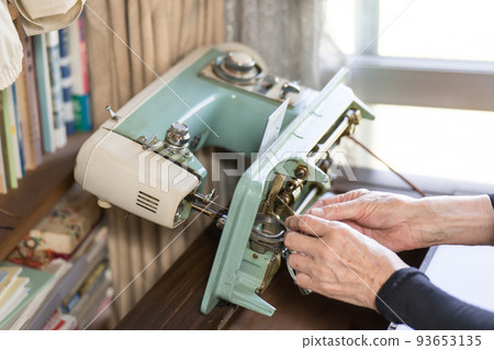Senior woman attaching bobbin to sewing machine Senior woman attaching bobbin to sewing machine 93653135