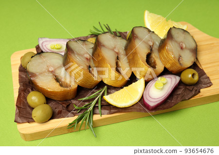 Concept of tasty food with smoked mackerel on green background Concept of tasty food with smoked mackerel on green background 93654676