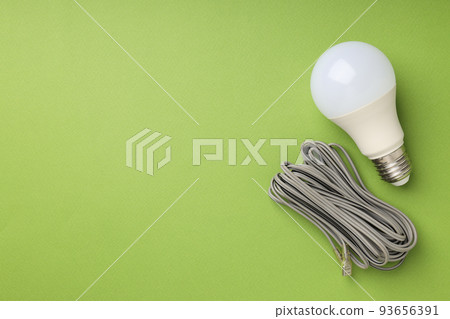 Energy saving bulb and wire on green background Energy saving bulb and wire on green background 93656391