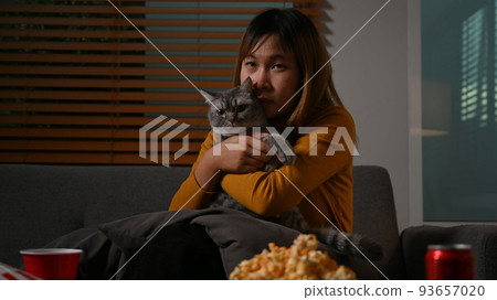 Young asian woman with her lovely cat watching TV at home. Leisure activity, relaxation, hobby concept Young asian woman with her lovely cat watching TV at home. Leisure activity, relaxation, hobby concept 93657020