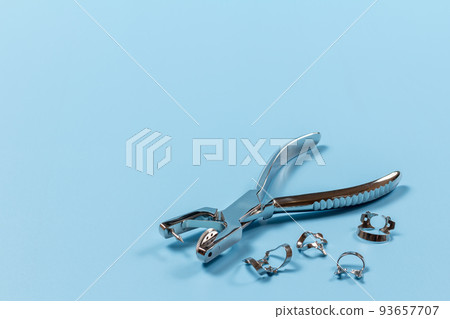 Dental hole punch and clamps on blue. Dental hole punch and clamps on blue. 93657707