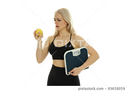 Sporty woman with apple and scales isolated on white background Sporty woman with apple and scales isolated on white background 93658059