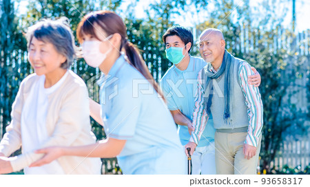 Rehabilitation Center Elderly people and care staff walking in the courtyard 93658317