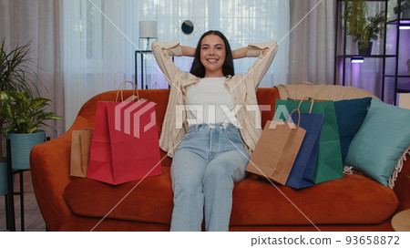 Happy adult girl shopaholic consumer came back home after online shopping sale with bags at home Happy adult girl shopaholic consumer came back home after online shopping sale with bags at home 93658872
