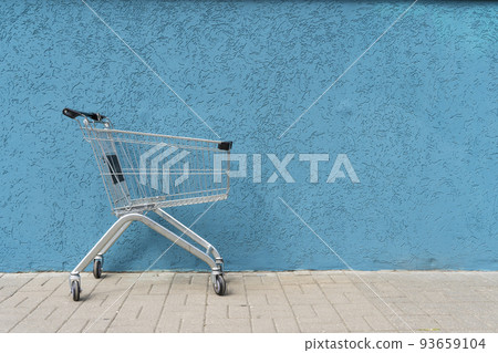 Supermarket cart trolley on empty colored wall background. Retail, sale, shopping concept. Supermarket cart trolley on empty colored wall background. Retail, sale, shopping concept. 93659104