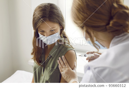 Preteen girl receives injection of antiviral vaccine against coronavirus in hospital. 93660312