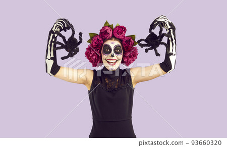 Cheerful woman with mexican traditional makeup for day of the dead posing with decorative spiders. 93660320