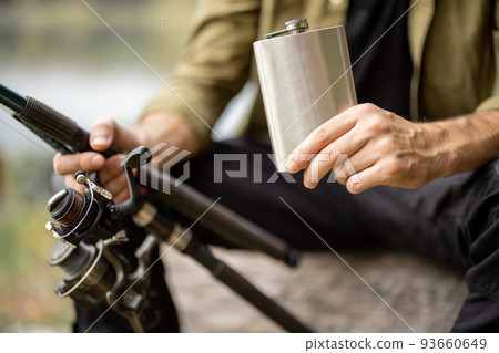 Man holding flask while fishing on lake 93660649