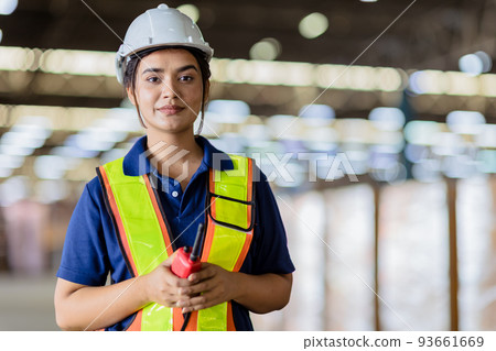 Portrait Indian woman worker supervisor with engineer safety suit work in large factory warehouse 93661669