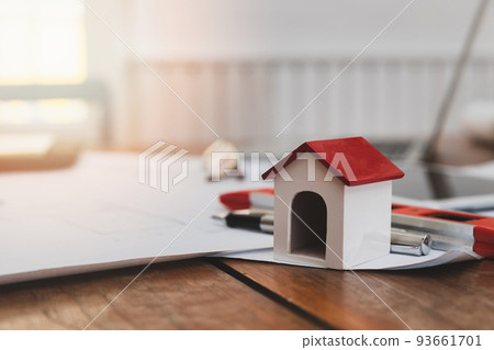 Business, architecture, building and construction concept - Architects house model with measurement tool and blueprints on architect desk 93661701