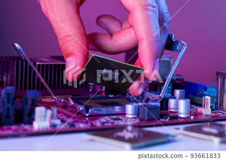 A man's hand inserts a processor into the motherboard chipset A man's hand inserts a processor into the motherboard chipset 93661833