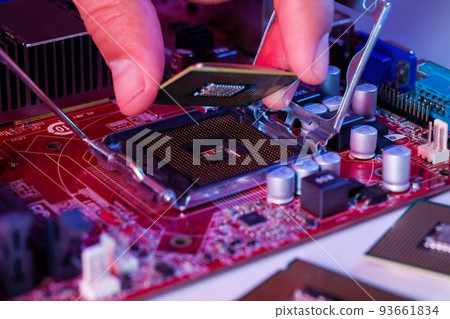 A man's hand inserts a processor into the motherboard chipset A man's hand inserts a processor into the motherboard chipset 93661834